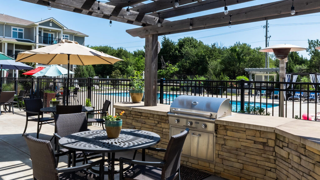 Outdoor grill station and patio tables with the pool in the background