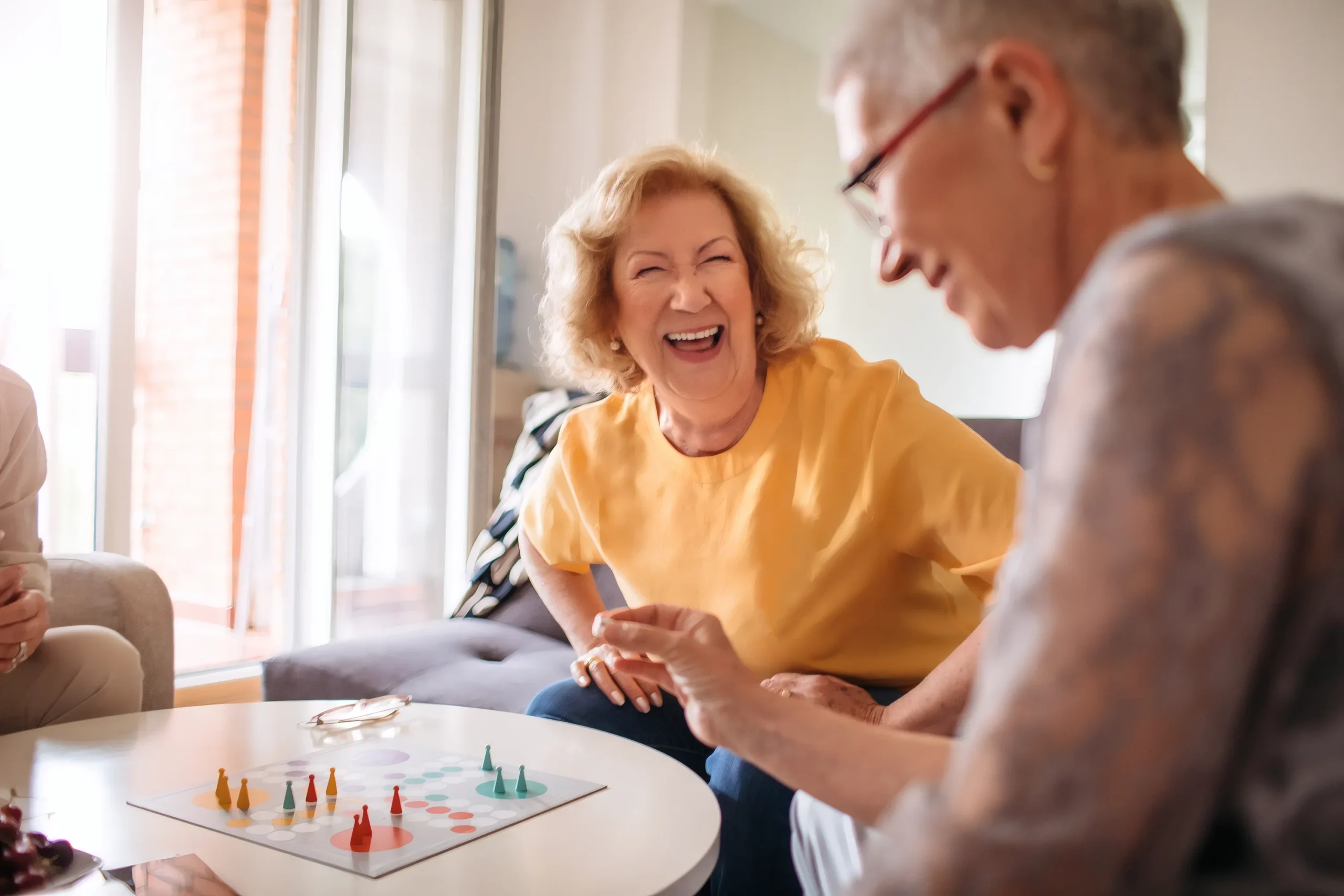 A smiling resident sharing a laugh with a friend over a board game