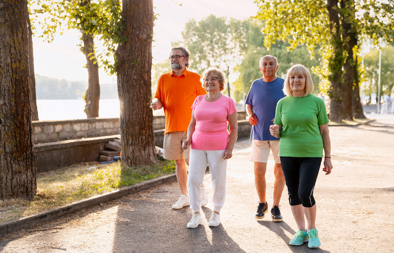Senior friends walking together enjoying outdoor exercise in park